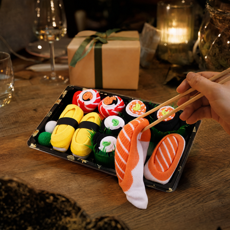 Sushi socks gift box on a set table, a piece being picked up with chopsticks